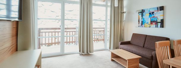 Der Wohnbereich besteht aus einer Sitzecke, einem Sofa, einem TV und dem Balkon.