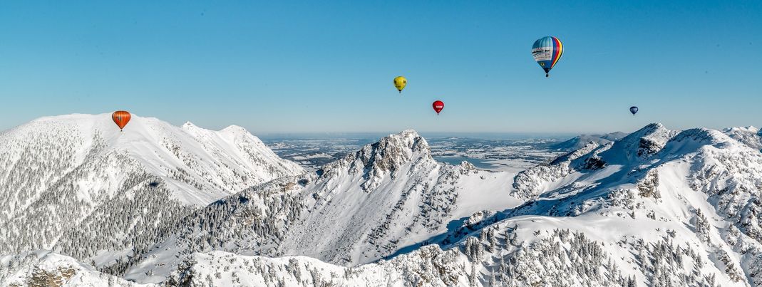 Farbenfrohe Heißluftballons über der verschneiten Bergwelt – das Ballonfestival im Tannheimer Tal verwandelt den Winterhimmel in ein faszinierendes Panorama.