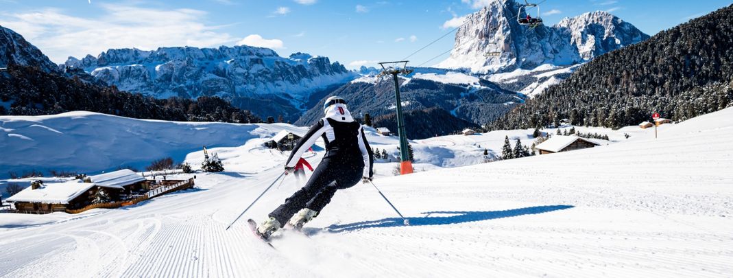 Vor der Dolomitenkulisse ziehen Skifahrer ihre ersten Schwünge.