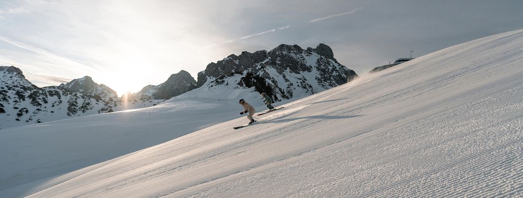 Perfekt präparierte Pisten und Sonne pur – im Tannheimer Tal genießen Skifahrer schwungvolle Abfahrten inmitten einer beeindruckenden Bergkulisse.