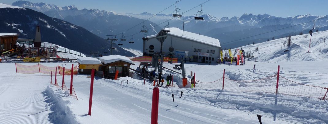Alles auf einen Blick - Das Übungsgelände (vorn), der Skiverleih an der Bergstation und der Skischulen-Sammelpunkt