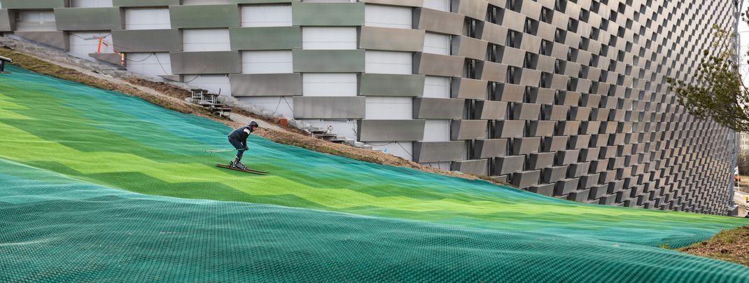 Die Piste führt an der Fassade des Industriegebäudes hinab ins Tal.