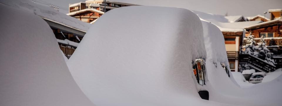 Die geparkten Autos sind in Alpe d'Huez von meterhohem Schnee bedeckt.