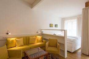 Studio mit Boxspringbett und Wohnbereich mit Ausziehcouch